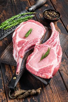 Marbled raw pork chops meat steak or tomahawk. Dark wooden background. Top view.