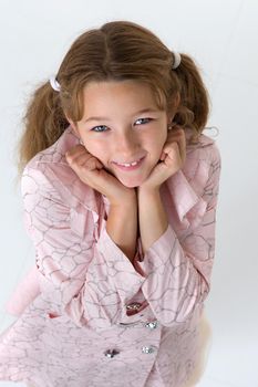 Beautiful little girl posing in the studio. She folded her arms near her face, and looks directly at the camera.Children's emotions concept. Close-up. Isolated on white background.