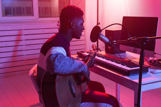 African american professional musician recording guitar in digital studio at home, music production technology concept