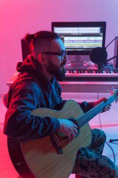 Create music and a recording studio concept - Bearded man guitarist recording electric guitar track in home studio.