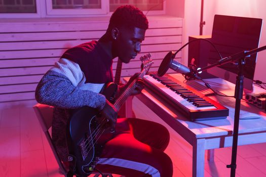 African american professional musician recording guitar in digital studio at home, music production technology concept