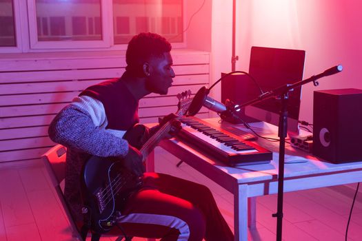 Create music and a recording studio concept - Bearded man guitarist recording electric guitar track in home studio.