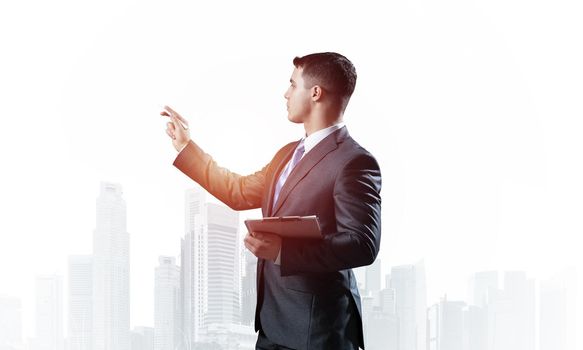 Handsome businessman standing and finger pointing at something. Side view of man in business suit and tie on background foggy cityscape. Financial specialist with raised hand promotion mockup.