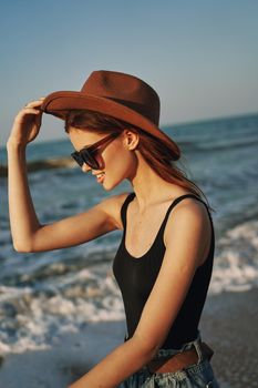 cheerful woman in sunglasses and a hat by the ocean walk summer. High quality photo