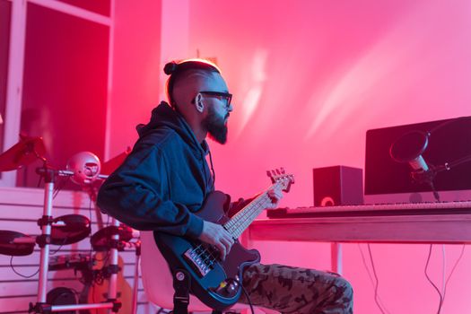 Create music and a recording studio concept - Bearded man guitarist recording electric guitar track in home studio.