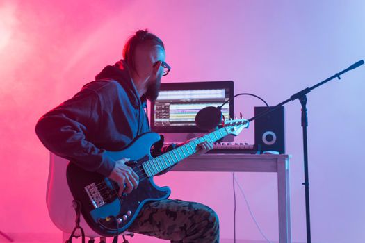 Create music and a recording studio concept - Bearded man guitarist recording electric guitar track in home studio.