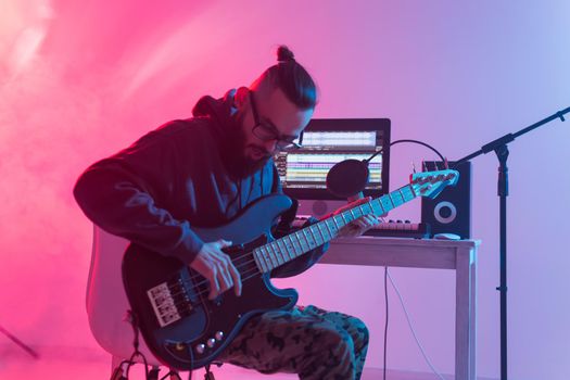 Create music and a recording studio concept - Bearded man guitarist recording electric guitar track in home studio.