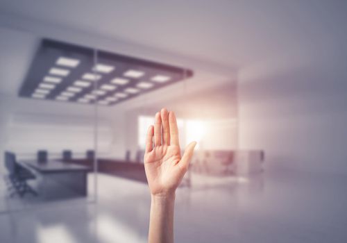 Close of woman hand touching screen with palm and office at background