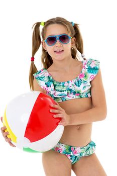 Pretty girl in swimsuit holding ball. Beautiful preteen girl with pigtails posing in studio against white background. Happy girl having summer vacation