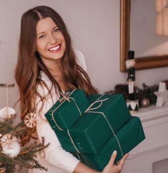 Christmas holiday and sustainable gifts concept. Happy smiling woman holding wrapped presents with eco-friendly green wrapping paper.