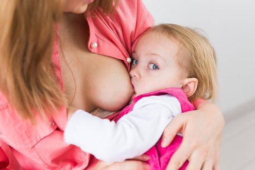 Lactation and motherhood concept - Young beautiful mother holding breastfeeding baby sitting on chair