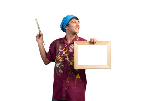 Young handsome painter artist holding paintbrush and blank canvas in frame. Portrait of happy painter isolated on white background. Creative hobby and artistic occupation. Art school student posing.