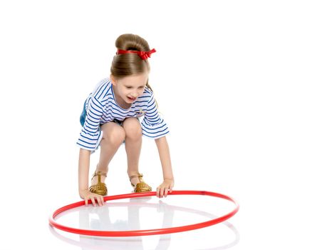 A cute little girl is playing with a hoop. The concept of children's games, morning exercises and fitness. Isolated on white background.
