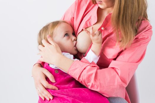 Mother breastfeeding baby in her arms at home. Young woman nursing and feeding baby. Concept of lactation infant.