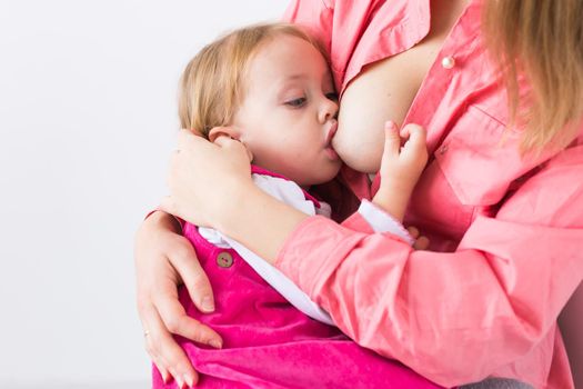 Mother breastfeeding baby in her arms at home. Young woman nursing and feeding baby. Concept of lactation infant.