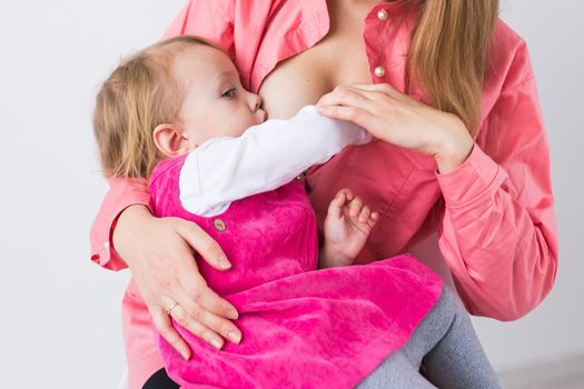 Mother breastfeeding baby in her arms at home. Young woman nursing and feeding baby. Concept of lactation infant.