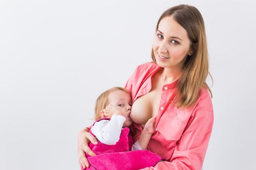 Mother breastfeeding baby in her arms at home. Young woman nursing and feeding baby. Concept of lactation infant.