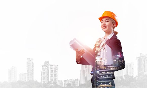 Beautiful woman architect standing with technical blueprints. Young specialist in safety helmet on background office buildings. Engineering and development company. Double exposure business concept.