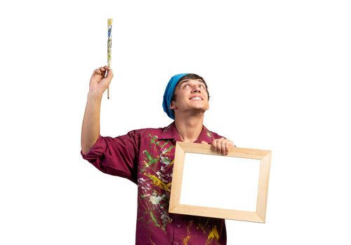 Young handsome painter artist holding paintbrush and blank canvas in frame. Portrait of happy painter isolated on white background. Creative hobby and artistic occupation. Art school student posing.