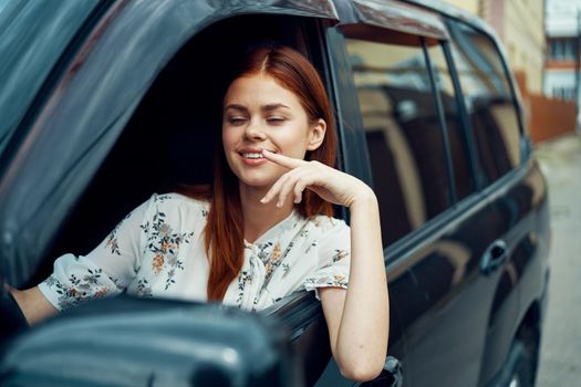 cheerful woman driving a car looks out of the window. High quality photo