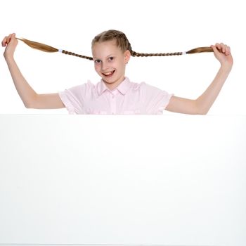 A beautiful little girl is pulling herself in pigtails. The concept of education, advertising, children's emotions. Isolated on white background.