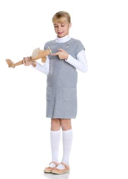 Happy little girl is playing with a wooden plane in the studio on a white background. The concept of emotions and children's games. Isolated.