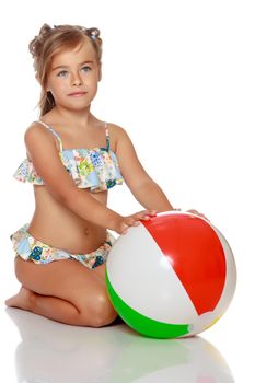 A little girl in a swimsuit is playing with a big ball. The concept of a family vacation at sea, happy childhood.Isolated on white background.