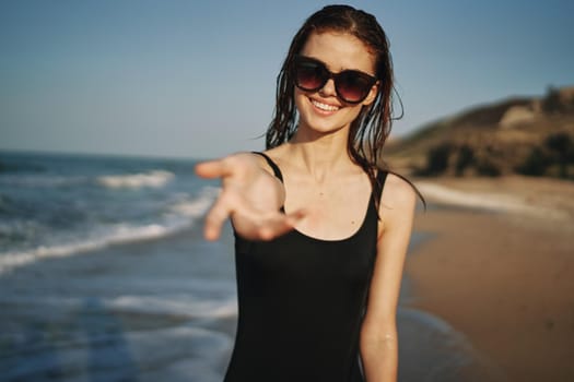 cheerful woman in a black swimsuit walking along the beach tropics summer. High quality photo