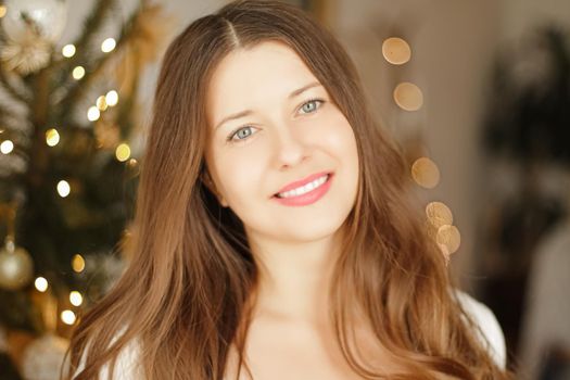 Christmas time and holiday mood concept. Happy smiling woman and decorated xmas tree lights on background.