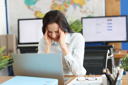 A young woman in the office is suffering from a headache. Anxiety and burnout at work. Stress and tension