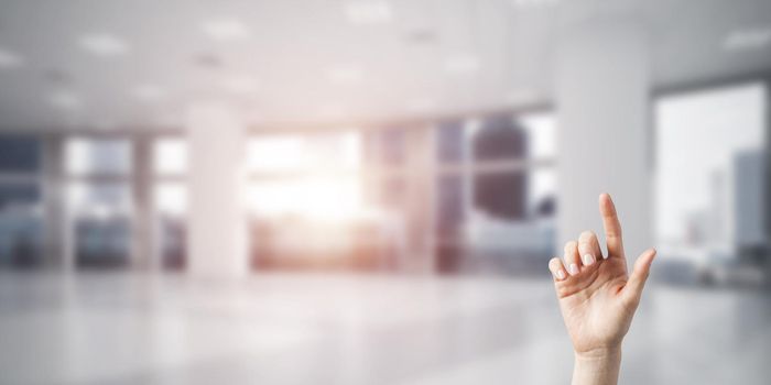 Close of woman hand touching screen with finger and office at background