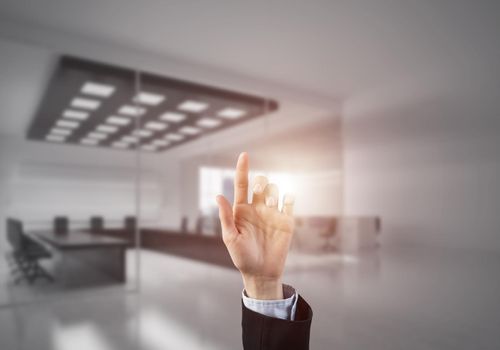 Close of businesswoman hand touching screen with finger and office at background