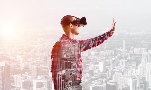 Young man with virtual reality headset or 3d glasses over cityscape background