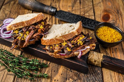 Sandwich with slow smoked pulled pork meat on white bread. wooden background. Top view.