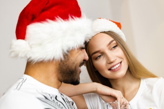 Cheerful attractive happy couple in Santa hats, close up portrait