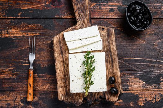 Fresh cheese feta with thyme and olives. Dark wooden background. Top view.