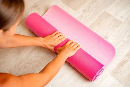 Young woman with long hair, fitness instructor in black sportswear, doing stretching and pilates on yoga mat at home. Female fitness yoga routine concept. Healthy lifestyle harmony and meditation
