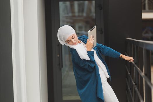 Beautiful Asian businesswomen wearing hijab using her tablet at outdoor.