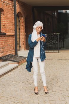 Portrait of young arabian muslim woman listening music with headphone and dancing. Feminism, woman independence and leisure concept
