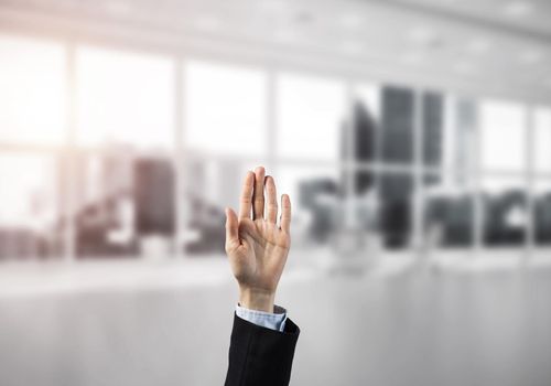 Close of businesswoman hand touching screen with palm and office at background