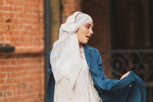 Portrait of young arabian muslim woman listening music with headphone and dancing. Feminism, woman independence and leisure concept