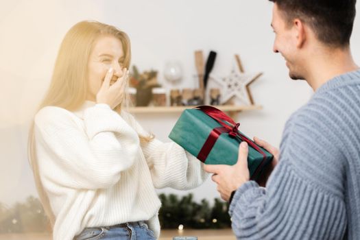 Sweet young couple opening Christmas gifts in the living room at home