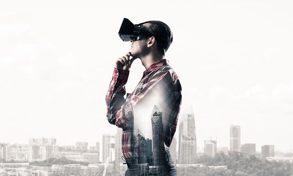 Young man with virtual reality headset or 3d glasses over cityscape background