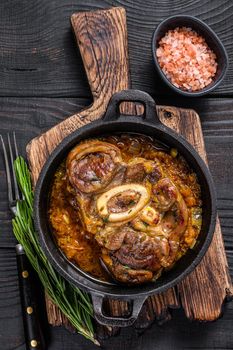 Stew veal shank meat OssoBuco, italian osso buco steak. Black wooden background. Top view.