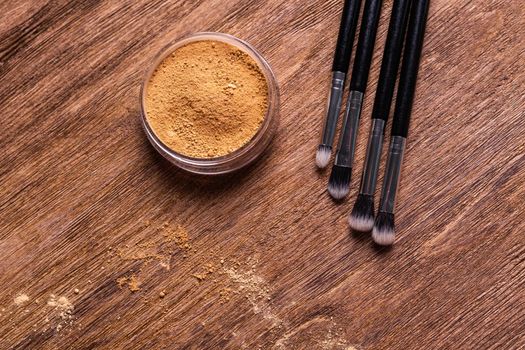 Mineral powder foundation with brush on a wooden background.