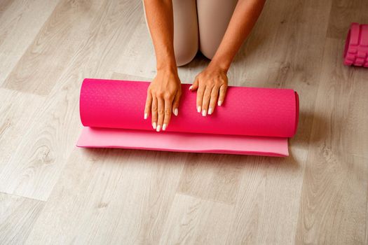 Young woman with long hair, fitness instructor in black sportswear, doing stretching and pilates on yoga mat at home. Female fitness yoga routine concept. Healthy lifestyle harmony and meditation