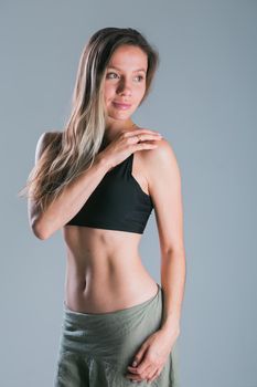 Fitness and diet concept. Portrait of young woman with perfect sporty body and pretty flat abs in sexy sportswear top on gray background