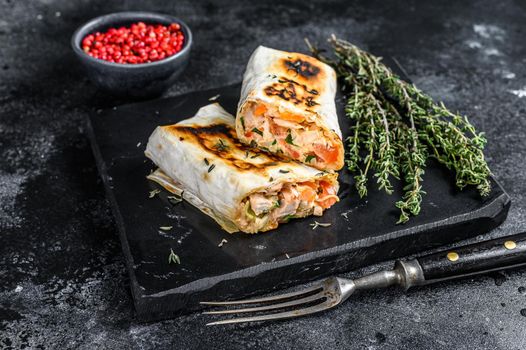 Doner kebab roll in a lavash with chicken and beef meat. Black Wooden background. Top view.