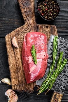 Raw lamb meat sirloin steak on a wooden cutting board. Black wooden background. Top view.