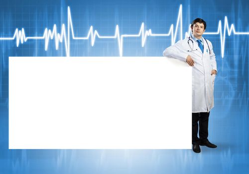 Young handsome doctor with white blank banner. Place your text